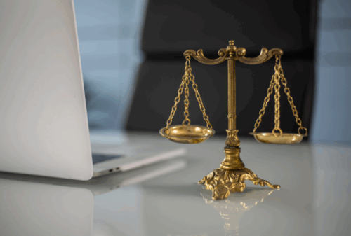 Image is of a lawyer's desk and laptop, with scales of justice in the forefront of the photo, concept of liability in truck accidents in Tennessee
