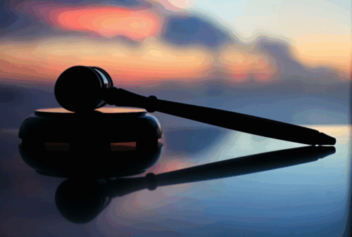 Image is of a judge's gavel sitting on a surface against a sunset background, concept of motorcycle requirements in Tennessee