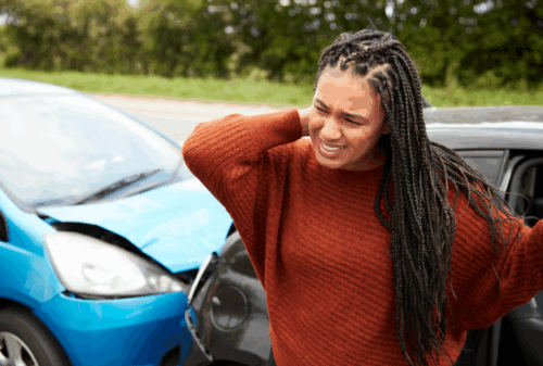 Image is of a woman holding her neck in pain after being hit from behind in a car accident, concept of airbags failed to deploy after a car accident