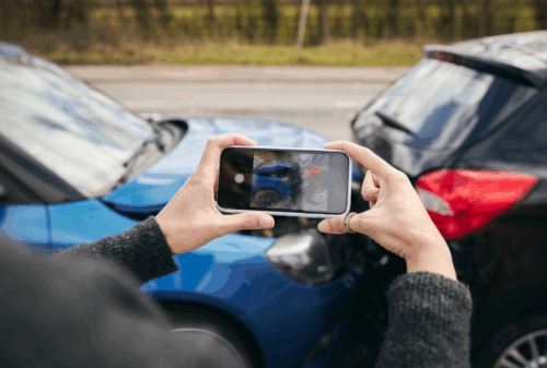 Image is of a woman taking photos of a rear end crash with her phone, concept of who is at fault in a rear-end collision in Nashville