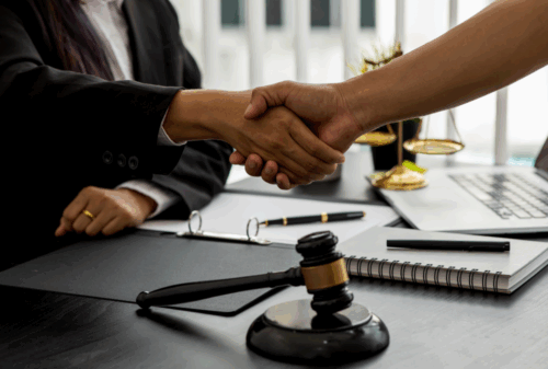 Image is of a lawyer sitting at their desk and shaking hands with a client, concept of who is at fault in a rear-end collision in Nashville