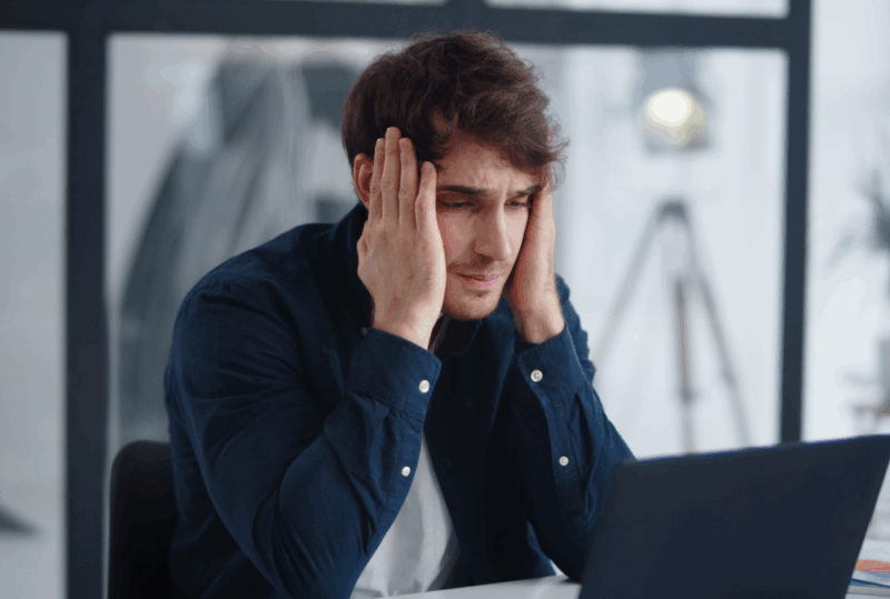 Image is of a upset man with his hands on his head while looking at his laptop, concept of how social media can hurt your Nashville car accident case.