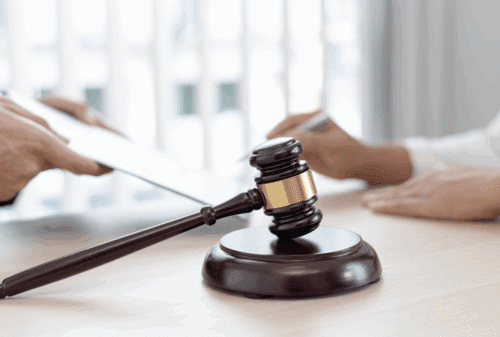 Image is of a lawyer and legal aide looking at a case, with a judge's gavel in the forefront, concept of Nashville pedestrian accident case.