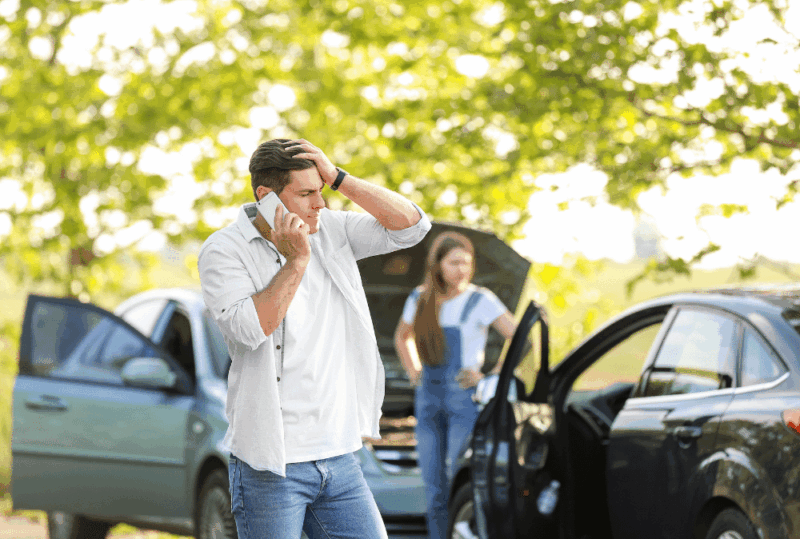 Image is of a man on the phone after a car accident with a woman, concept of common mistakes after a car crash in Nashville