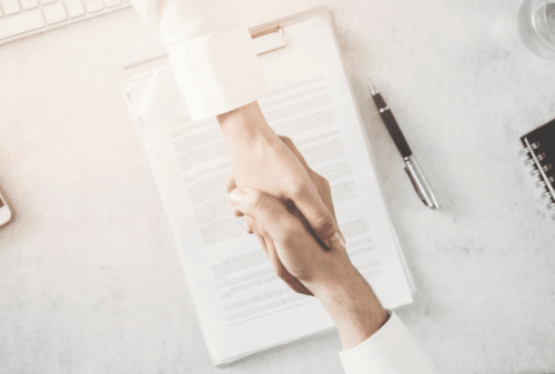 Image is of a closeup of a handshake between a lawyer and client, concept of suing after being hit by a car while biking in Nashville
