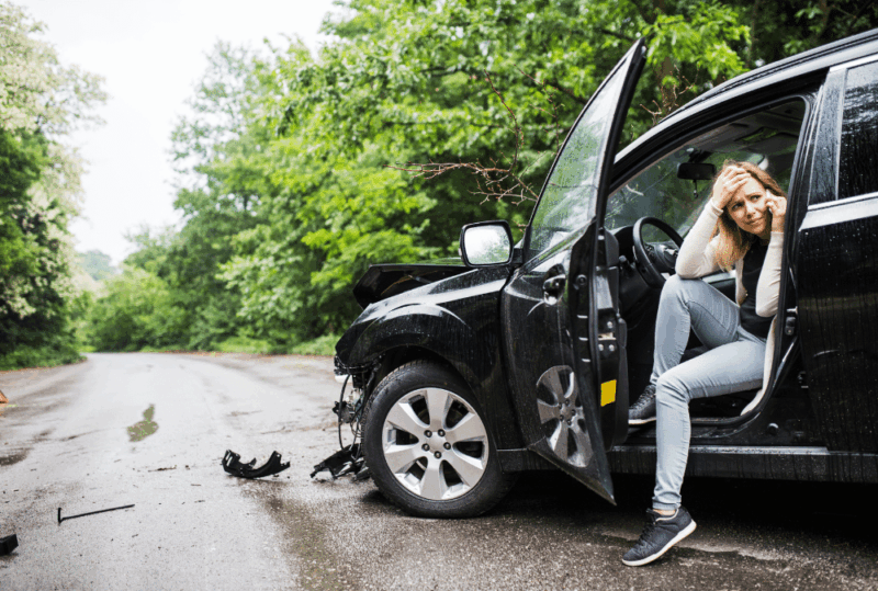 Image is of a woman in her car after an accident while on the phone calling for help, concept of how to handle a hit-and-run accident in Nashville