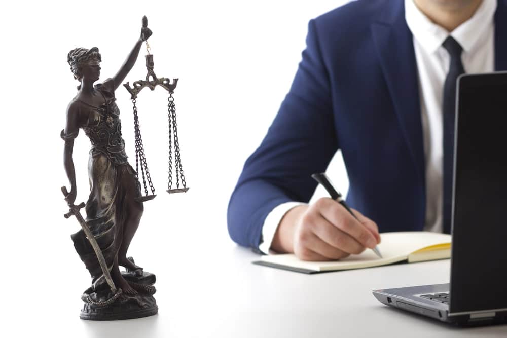 Image is of a legal professional reviewing case notes beside a justice statue, concept of truck accidents in Nashville and liability analysis.