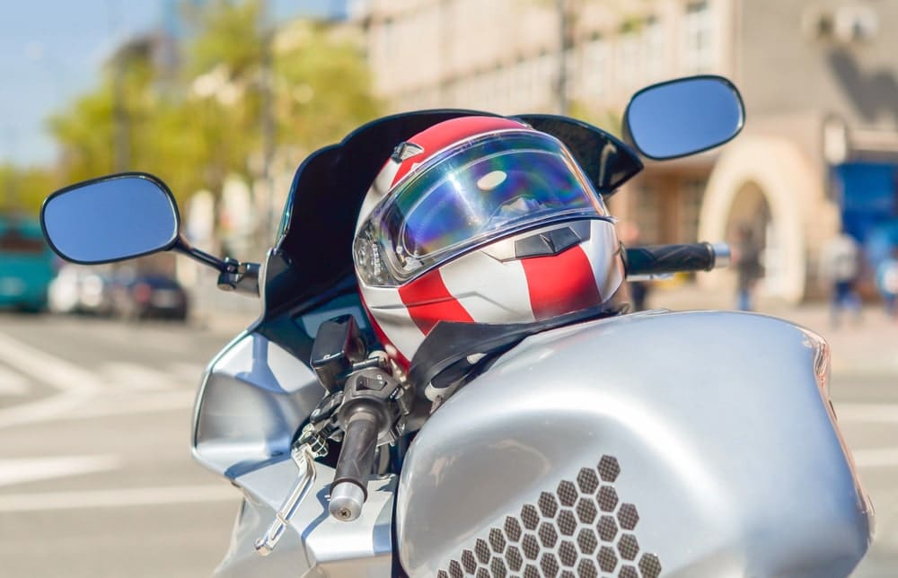 Image is of a motorcycle helmet resting on a parked bike in an urban setting, symbolizing helmet compliance issues that may impact motorcycle accident claims.