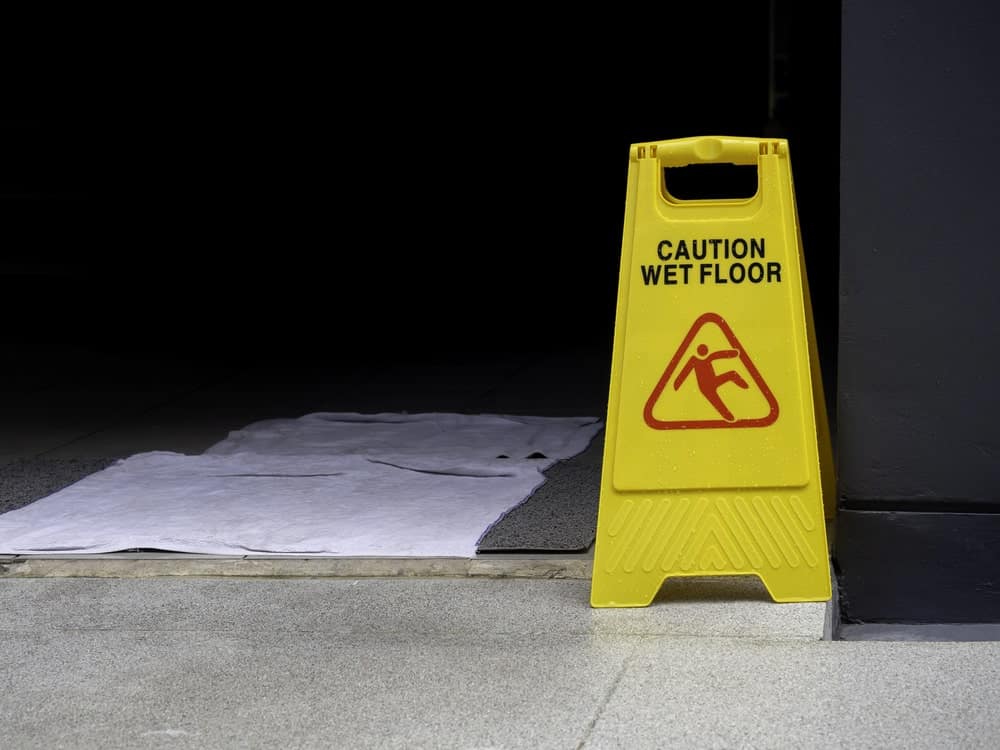 Image is of a caution wet floor sign placed near an entrance, illustrating hazardous conditions that commonly lead to Tennessee slip and fall accidents.