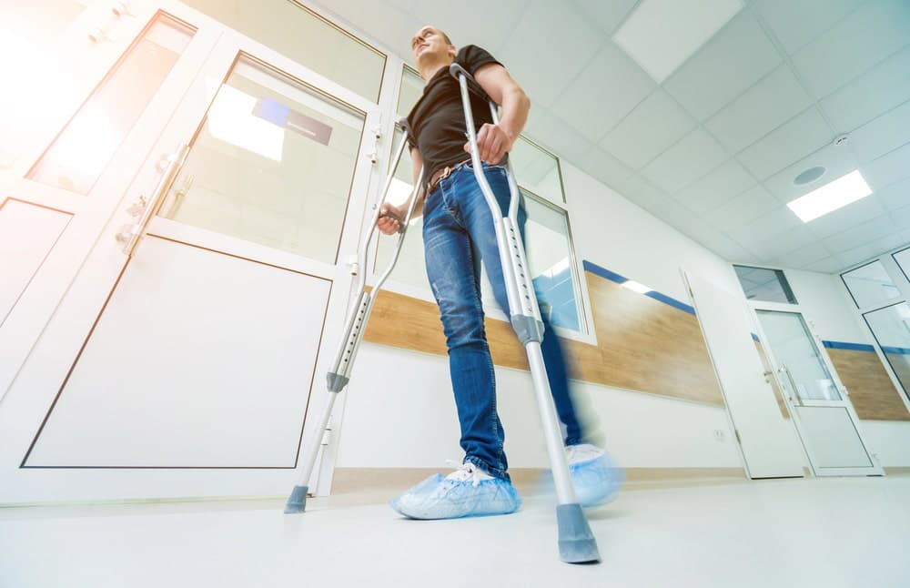 Image is of an injured individual walking with crutches inside a building, representing injury outcomes often seen in Tennessee slip and fall accidents.