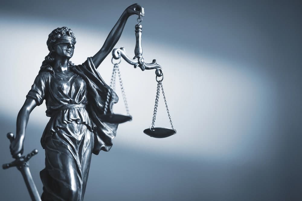 Image is of a Lady Justice statue holding balanced scales, symbolizing the legal responsibilities and insurance issues involved after a motorcycle crash in TN.