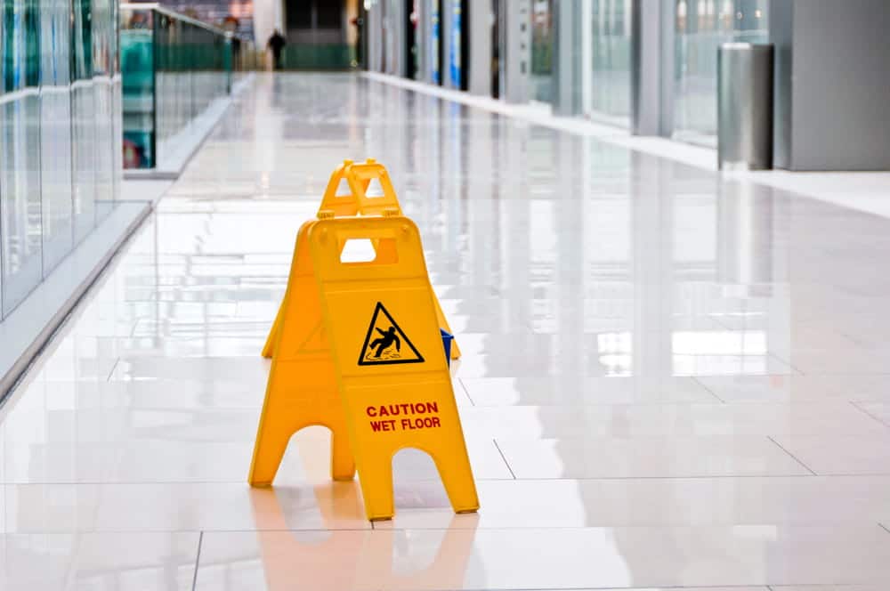 Image is of a wet floor caution sign inside a commercial building, highlighting indoor hazards that often lead to slip and fall claims.