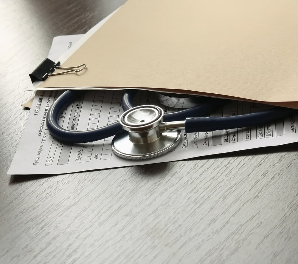 Image features a folder covering medical forms with a stethoscope, highlighting the role of medical records in proving medical costs after a dog bite for damage recovery