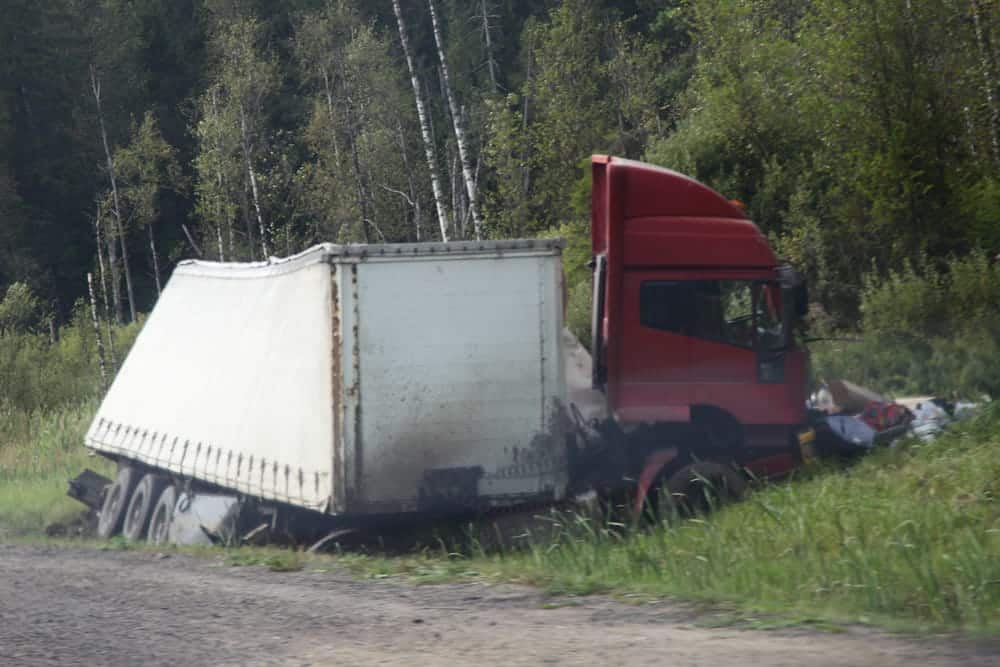 Image is of a jackknifed semi truck off the road in a rural area, concept of accident damage following a truck crash in Tennessee.
