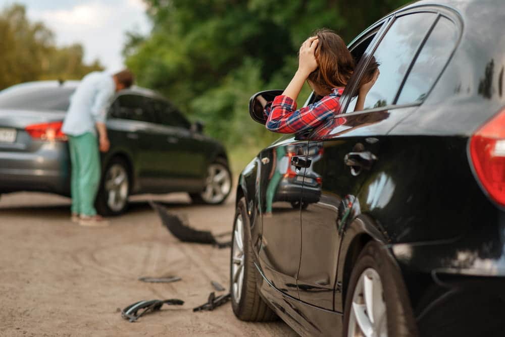 Image is of drivers stopped at a roadside crash scene holding their heads in distress, representing the physical and emotional impact of car accidents in Nashville.