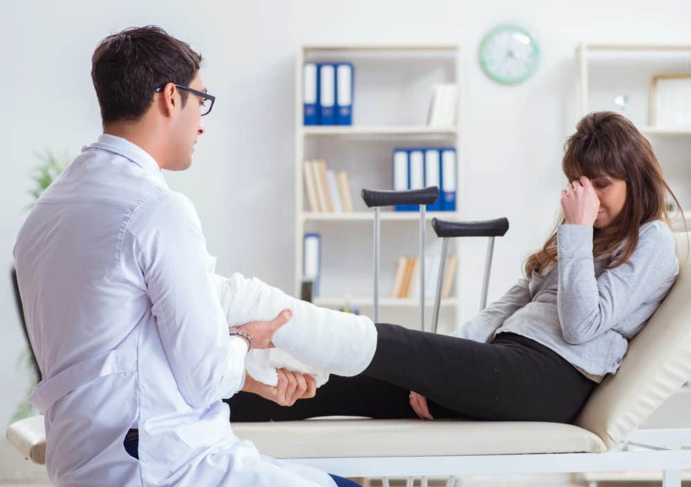 Image is of a patient receiving medical care for a leg injury on an examination table, reflecting orthopedic injuries often seen after car accidents in Nashville.