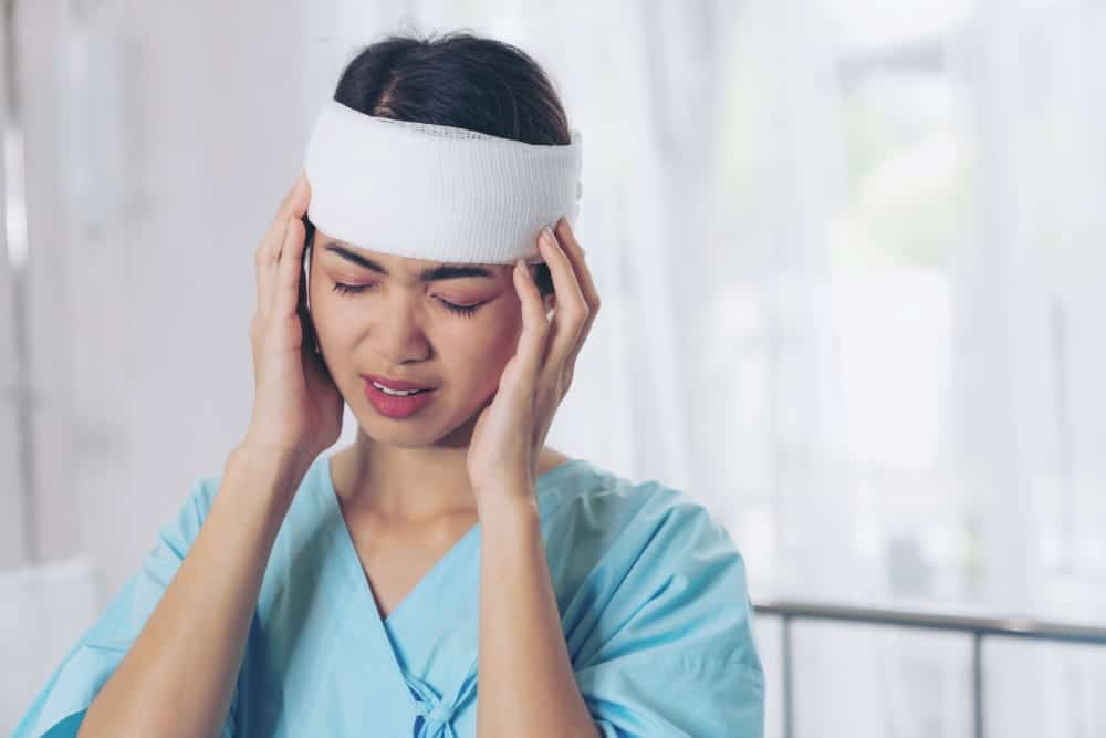 Image is of a woman holding her head with a bandage, representing medical impact after a slip and fall in TN.