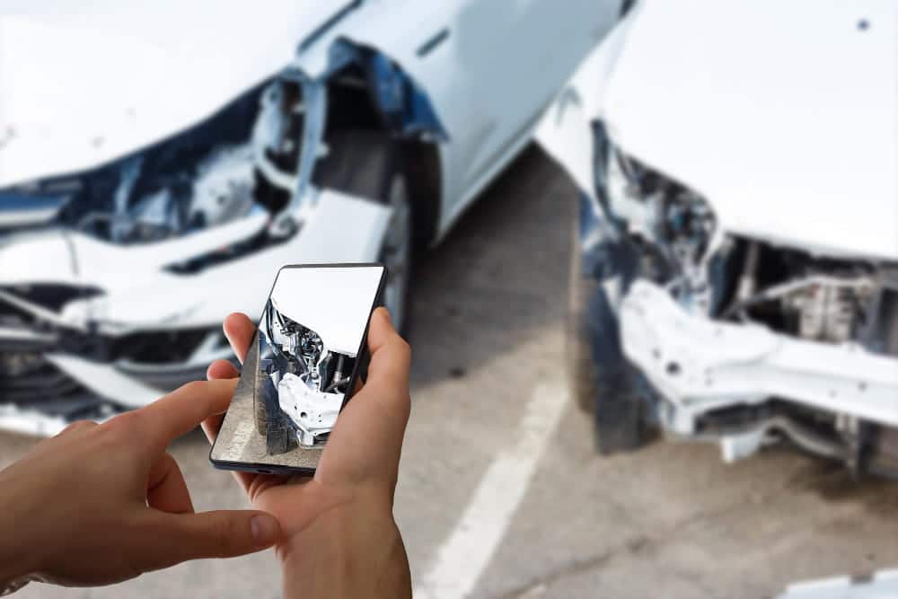 Image is of a person taking photos of vehicle damage with a smartphone after a collision, illustrating documentation steps in Tennessee car accidents and how fault may be evaluated.