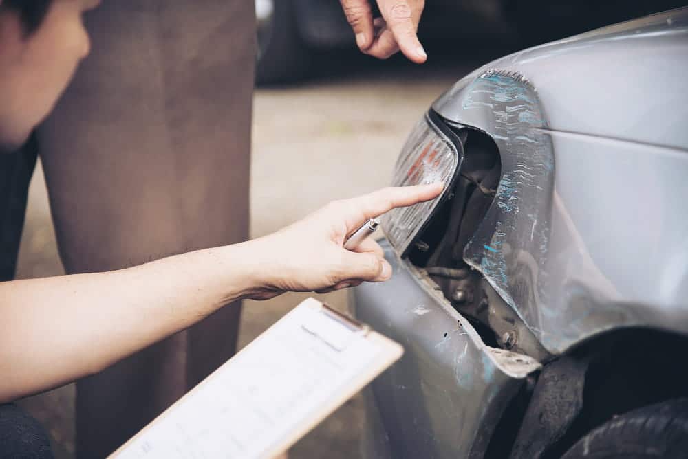 Image is of an individual pointing at a damaged headlight while reviewing accident details, representing evidence assessment in Tennessee car accidents and comparative fault analysis.