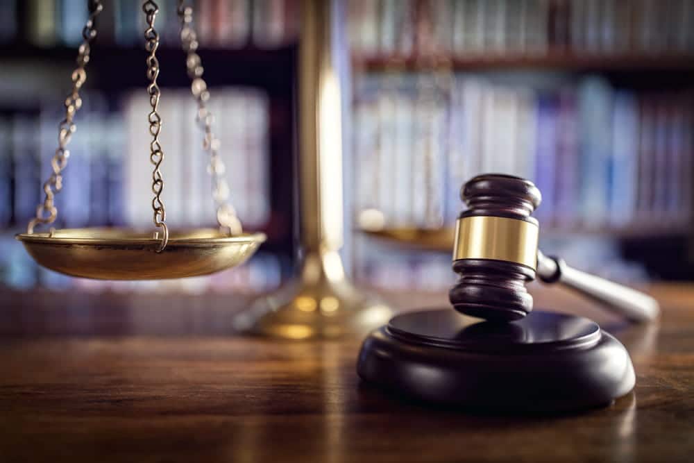 Image is of a wooden gavel and the scales of justice in a law library, concept of pursuing a legal claim after a motorcycle crash in Nashville.
