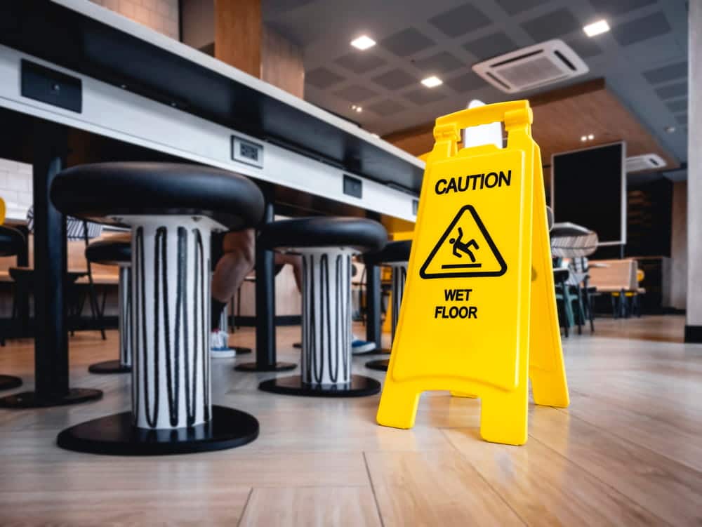 Image is of a yellow caution sign placed on a wet restaurant floor, highlighting a common cause of a slip and fall in Nashville.