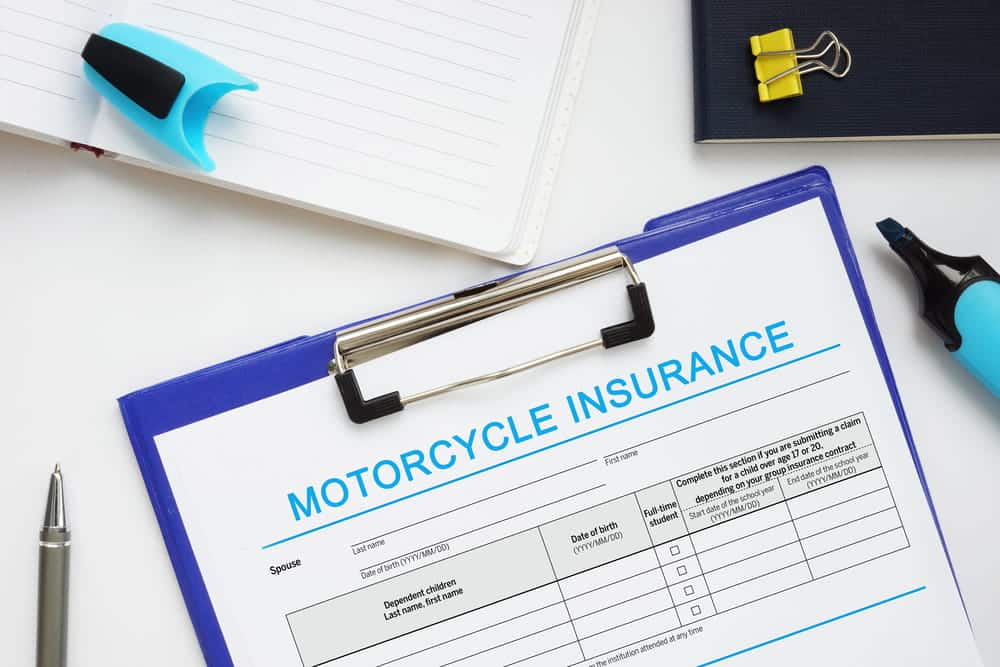 Image is of a motorcycle insurance claim form on a clipboard with office supplies, showing documentation steps after an accident in Nashville
