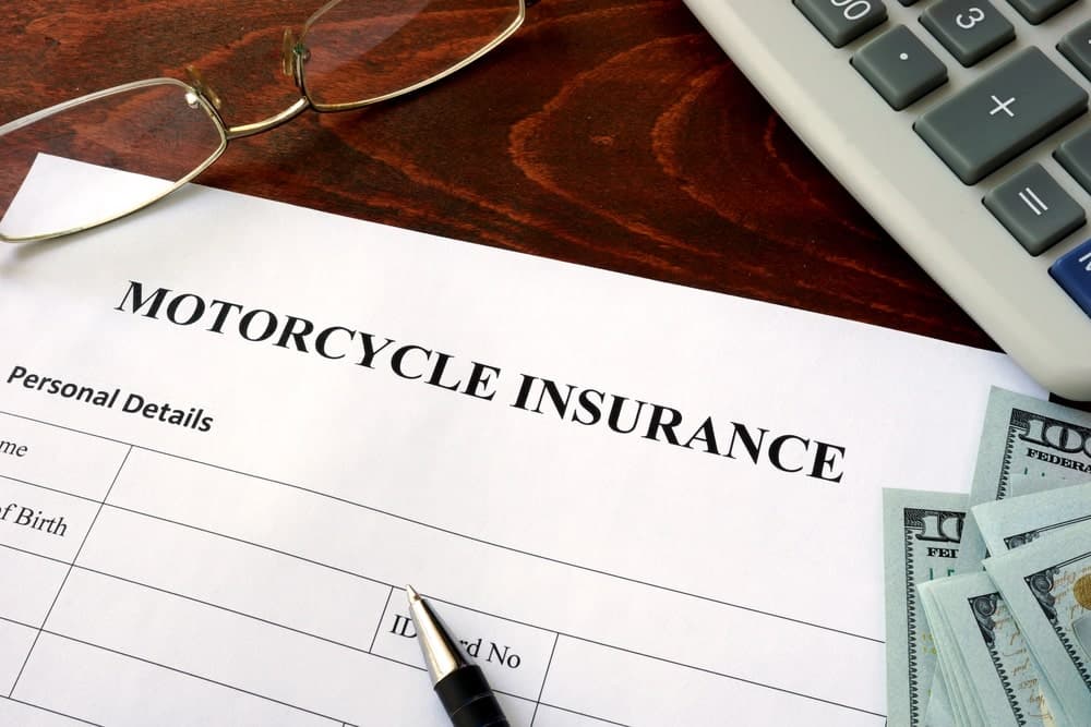Image is of a motorcycle insurance document with cash and a pen on a desk, representing financial claims after an accident in Nashville