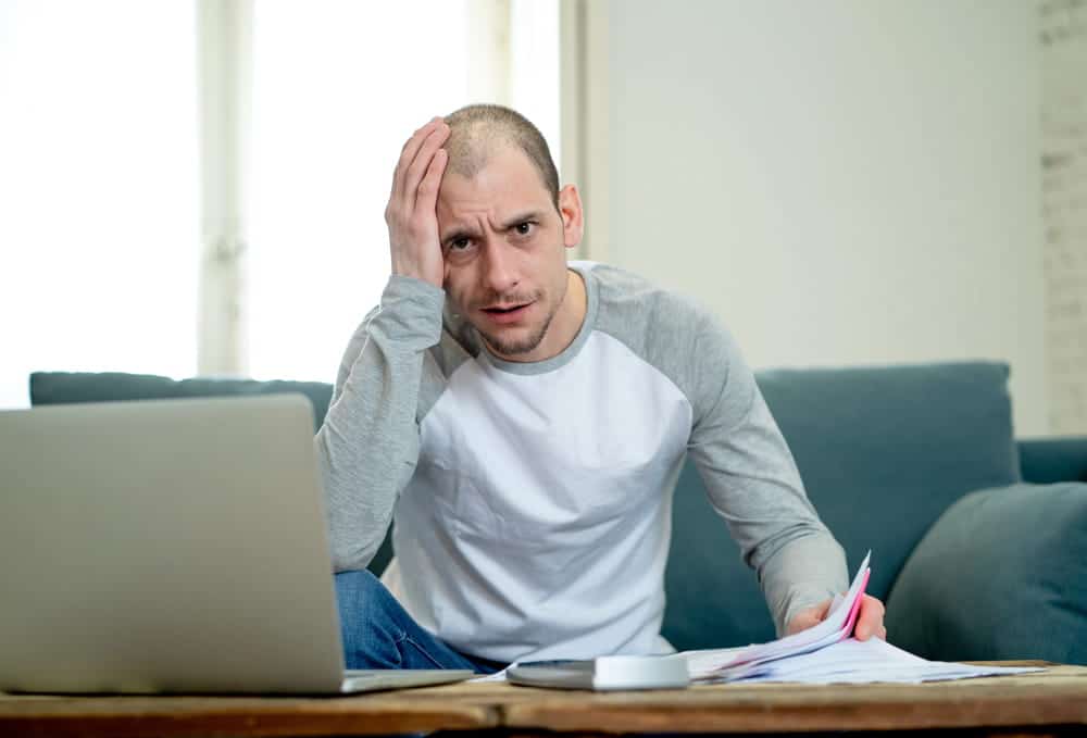 Image is of a stressed man reviewing bills and documents, illustrating financial strain after a car accident in Nashville