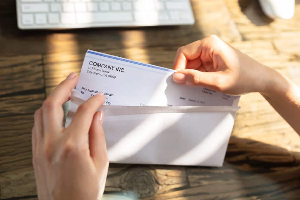 Image is of a person opening a paycheck envelope, representing lost income concerns after a car accident in Nashville