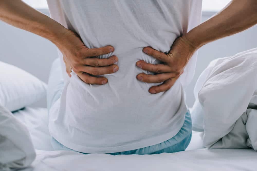 Image is of a person holding their lower back in pain, concept of slip and fall injuries in Nashville causing back strain