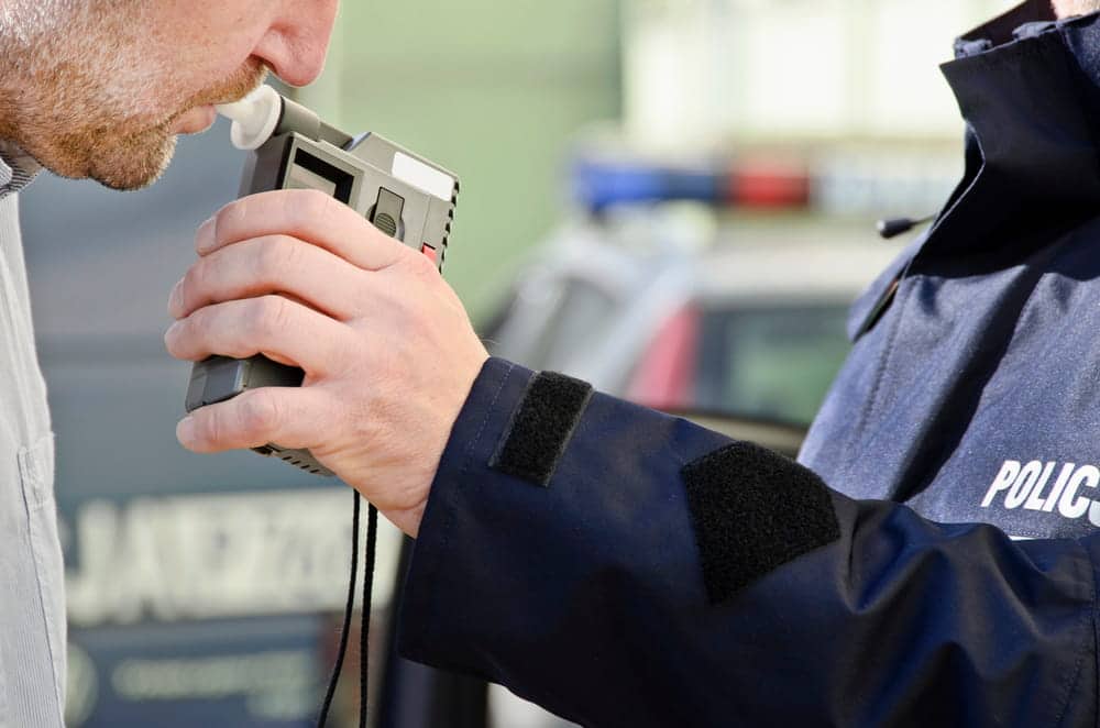 Image is of a law enforcement officer administering a breath test during a traffic stop, concept of a DUI motorcycle accident investigation and alcohol testing.