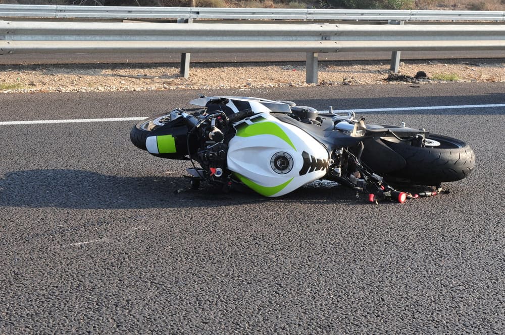 Image is of a motorcycle lying on a roadway after a collision, concept of a DUI motorcycle accident and the immediate aftermath of a crash.
