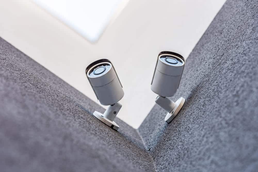 Image is of security cameras mounted on a building, concept of surveillance footage supporting a slip and fall claim by documenting the accident area.