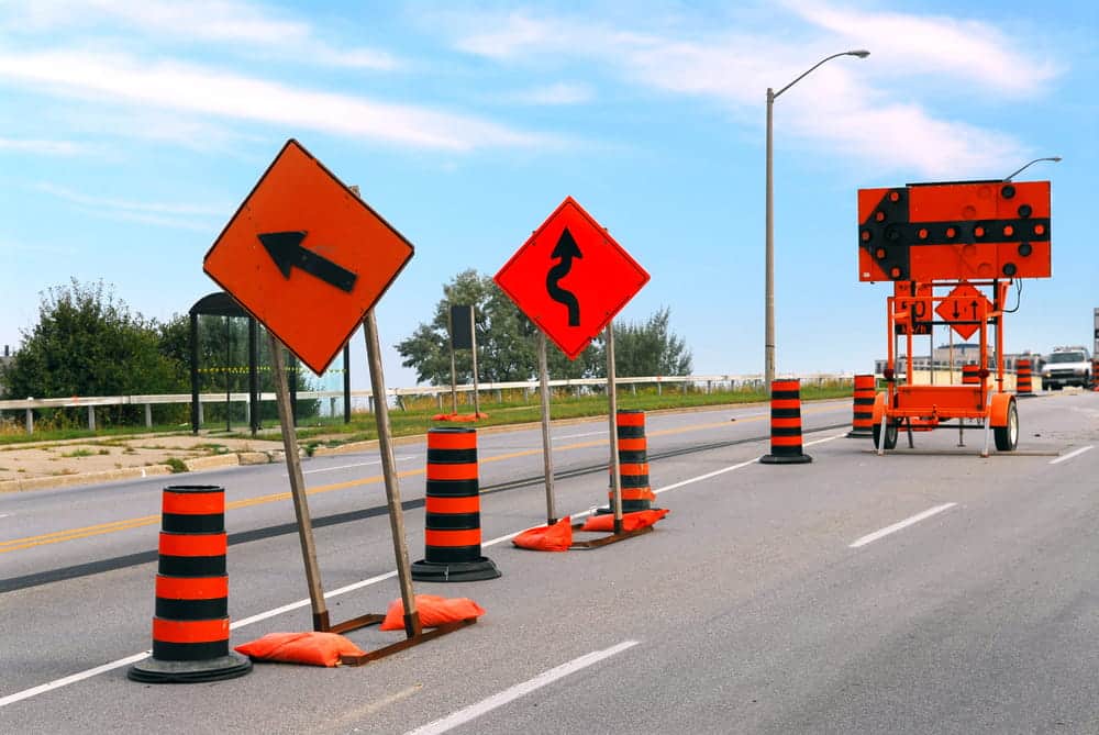 Image is of a roadway with construction signs and traffic barrels, concept of construction zone hazards leading to motorcycle crashes in Nashville.