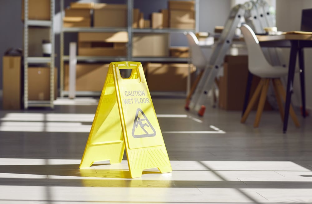 Image is of a wet floor warning sign inside a commercial building, concept of a slip and fall case.