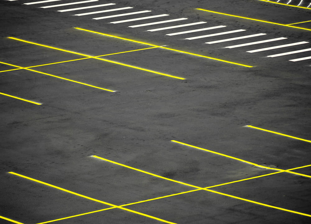 Image is of a parking lot with marked spaces and pedestrian crossings, concept of slip and fall accidents.