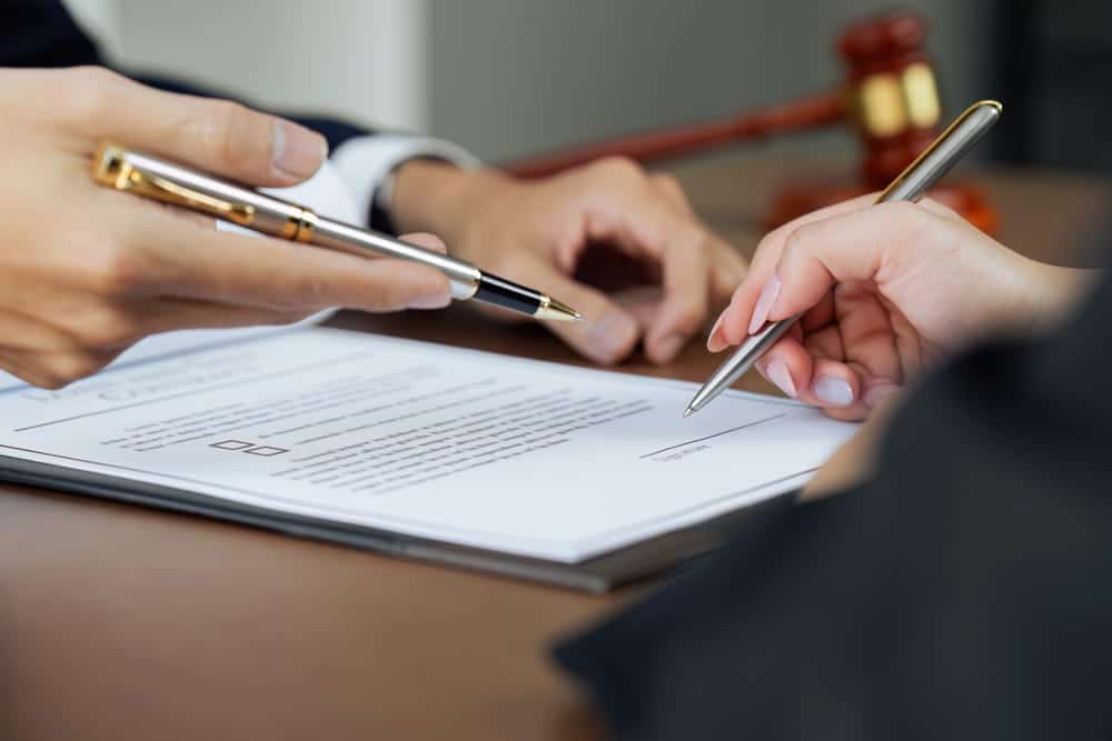 Image is of a client signing legal documents during a lawyer consultation, concept of preparing a dog bite claim before the filing deadline.