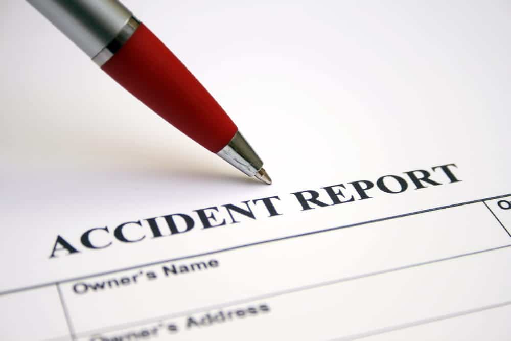 Image is of an accident report and pen, representing police documentation prepared after a car crash.