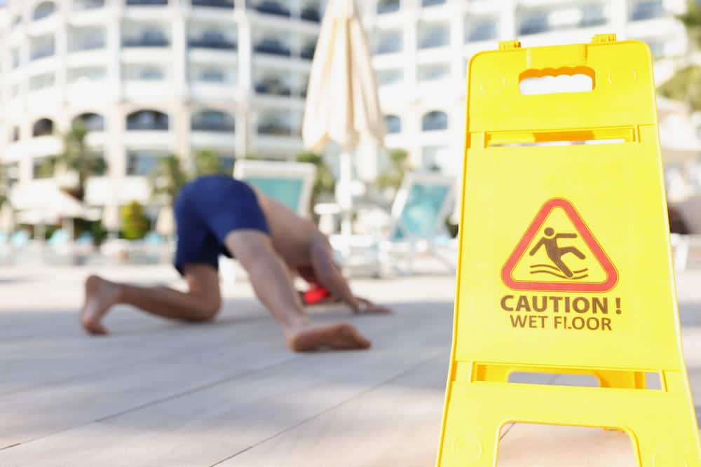 Image is of a person falling near a wet floor warning sign, concept of a hotel slip and fall accident.