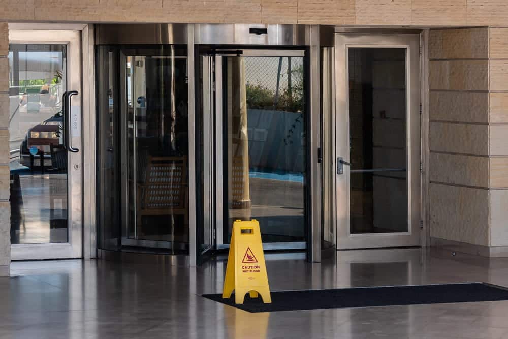 Image is of a wet floor warning sign near a hotel entrance, representing safety precautions related to a slip and fall accident.