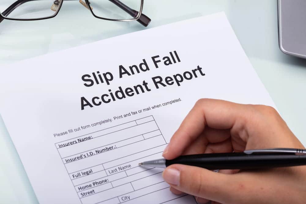 Image is of a person completing an accident report, concept of documenting evidence for a slip and fall claim.