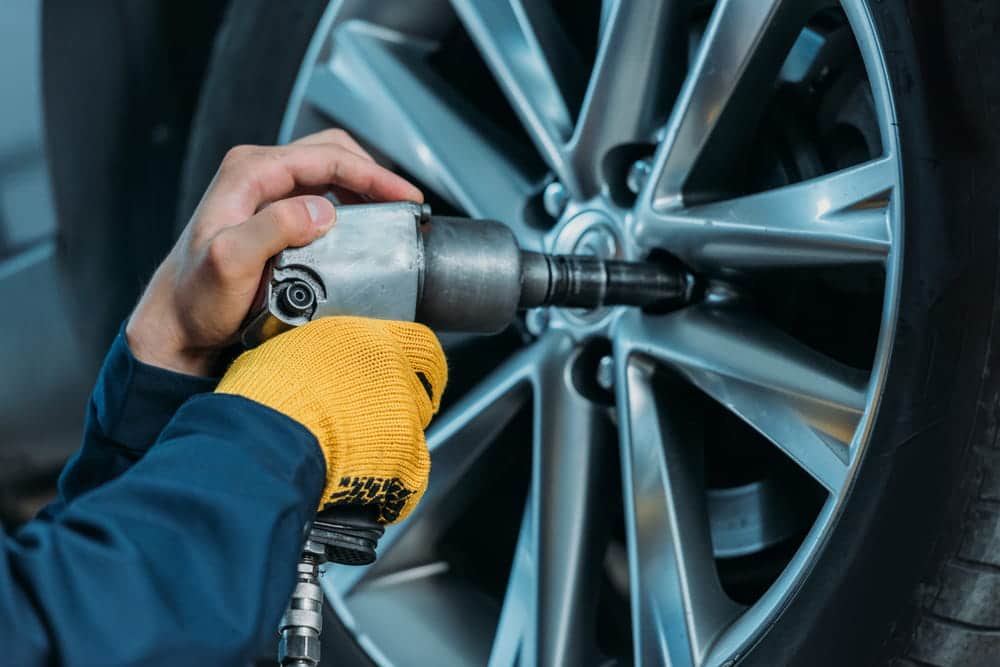 Image is of a mechanic tightening a vehicle wheel, concept of maintenance liability when a truck tire blows out.