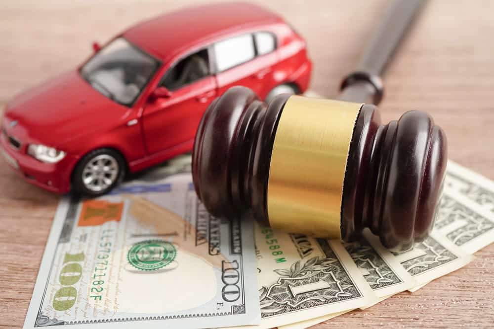 Image is of a car, judge’s gavel, and money, representing compensation after a car accident in Nashville.