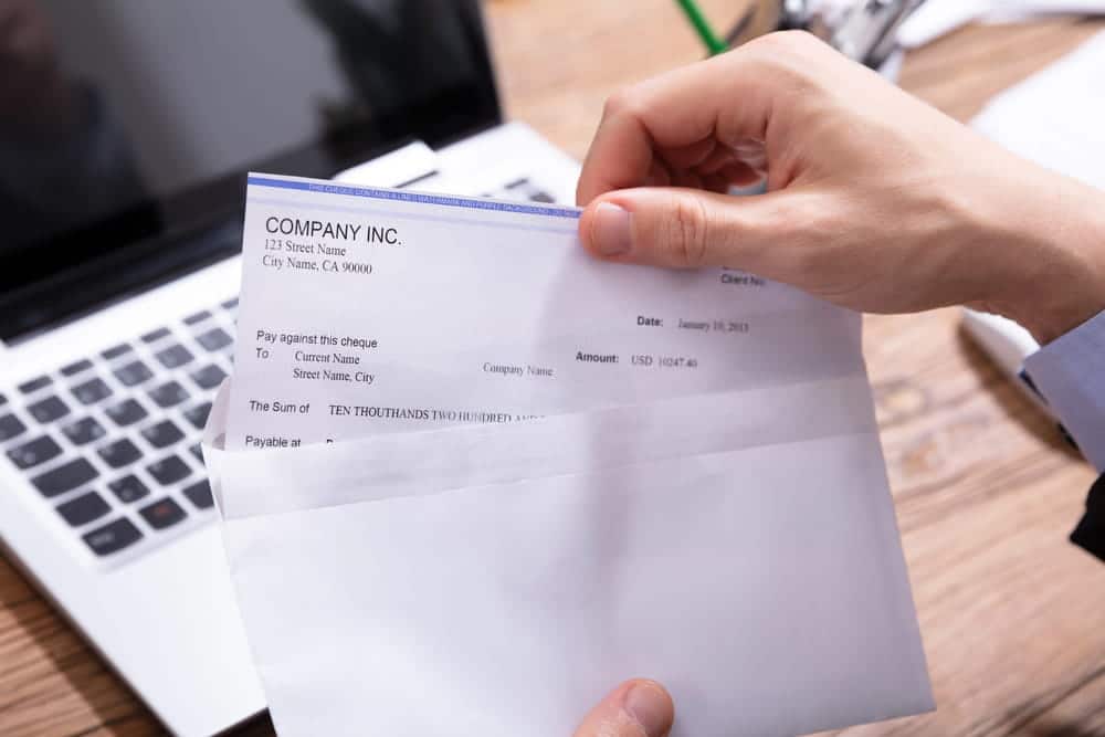 Image of a person examining a paycheck beside a laptop, representing wage documentation needed to establish lost income after a dog attack.