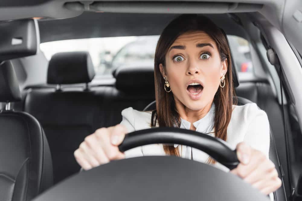 Image is of a shocked woman gripping the steering wheel of a car, concept of rental car accident in Nashville and immediate driver reactions.
