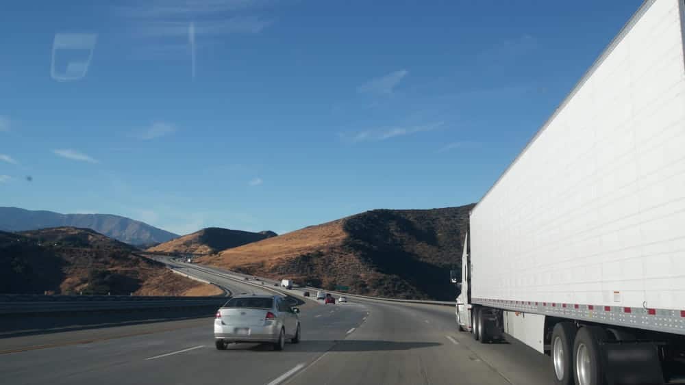 Image is of a semi truck traveling beside a passenger vehicle, concept of traffic risks involving truck crashes in Nashville.