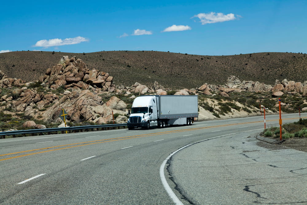 Image is of a semi truck traveling around a curved roadway, concept of wide turns and truck crashes in Nashville.